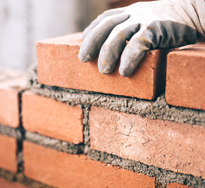 Close up of industrial bricklayer installing bricks on construction site