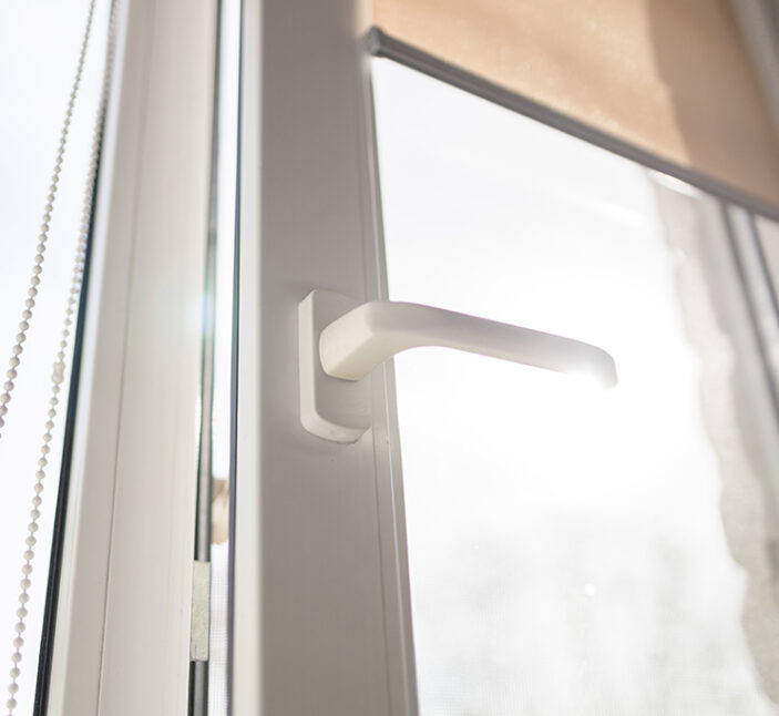 Roll Blinds on the windows, the sun does not penetrate the house. Modern white plastic pvc window with forest background at home, closeup view. Home interior