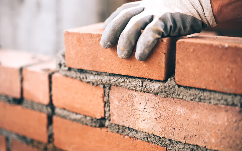 Close up of industrial bricklayer installing bricks on construct Close up of industrial bricklayer installing bricks on construction site