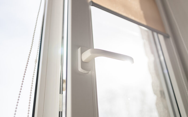 Roll Blinds on the windows, the sun does not penetrate the house. Modern white plastic pvc window with forest background at home, closeup view. Home interior